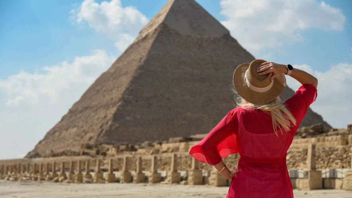 A traveler in a sun hat facing the Pyramid of Khafre on a private luxury Egypt tour, Giza, Egypt
