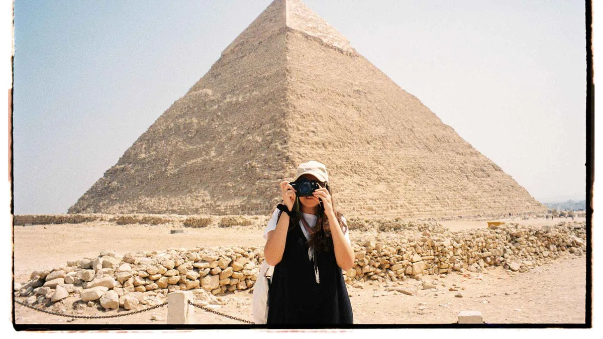 A traveler photographing the Pyramid of Khafre on an 8-day luxury Egypt tour with a Nile cruise, Giza, Egypt