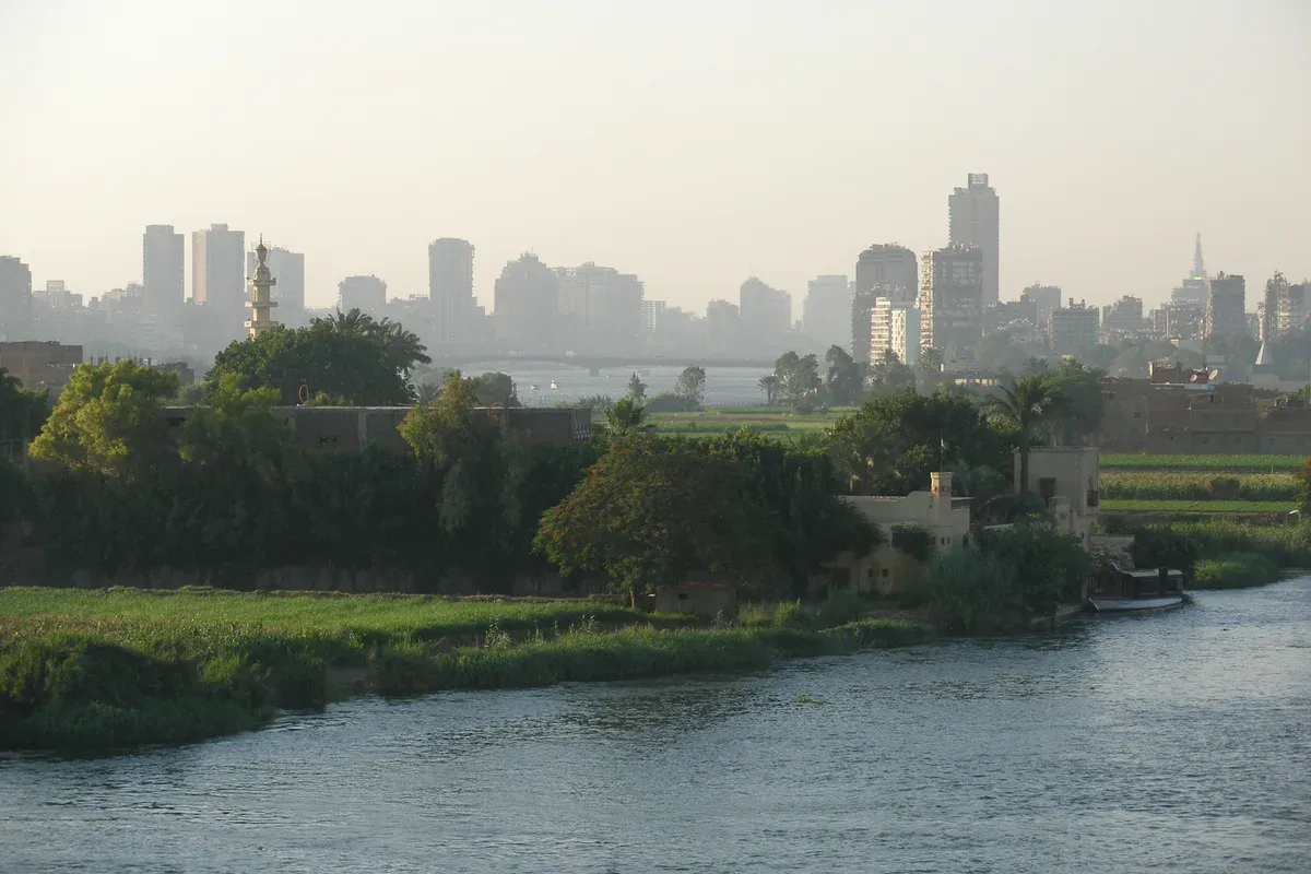 The Cairo skyline seen from the Nile with a minaret and green riverbank on a luxury Egypt tour, Cairo, Egypt