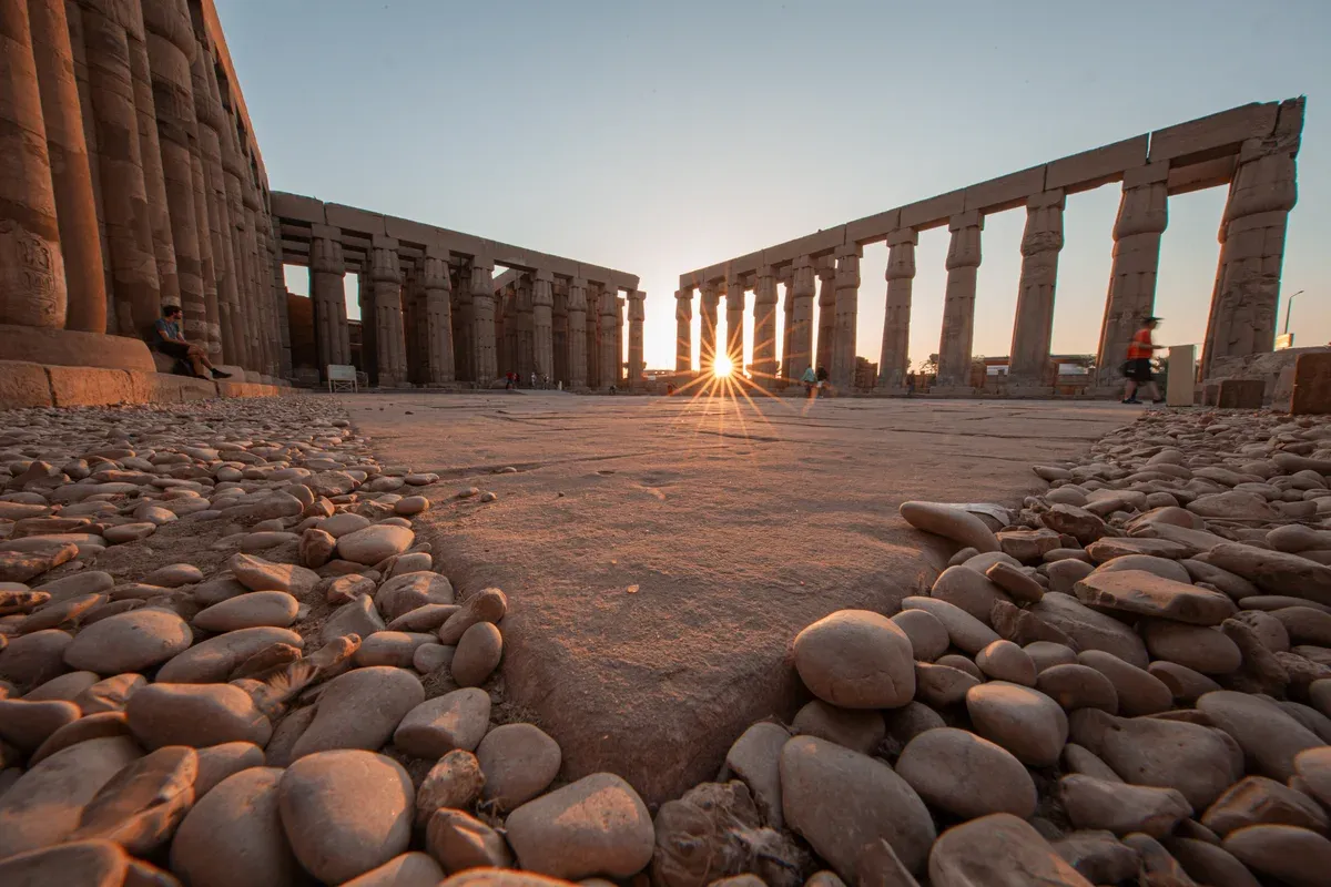 The sun setting between the colonnades of Luxor Temple on a luxury Egypt tour, Luxor Temple, Luxor, Egypt