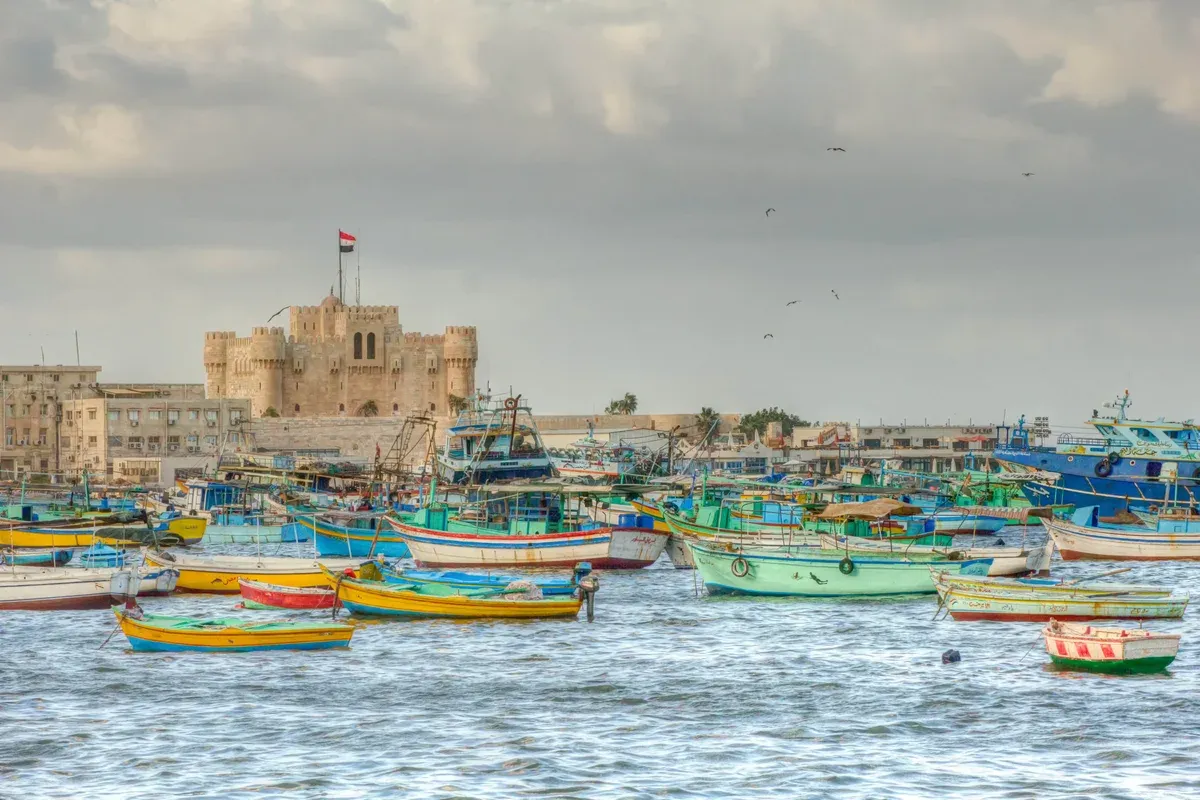 Colourful fishing boats in front of the Citadel of Qaitbay on a luxury Egypt tour, Alexandria, Egypt
